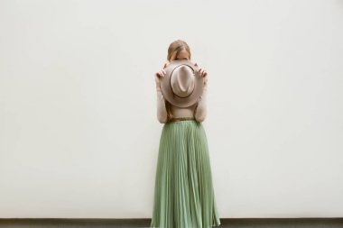 Şapkalı, Kızıl saçlı genç kız kılığında bej bluz ve gezinti pileler etek, ışık sokak backgraund üzerinde. Moda ve şık konsept.