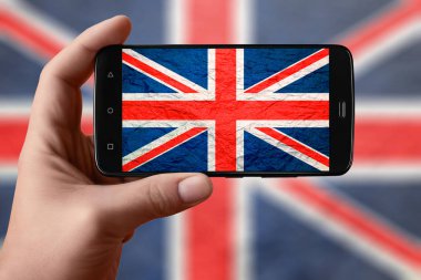 Telefon ekranında Britanya bayrağı var. Akıllı telefon el kamerasıyla bayrak çekiyor.. 