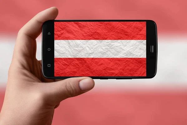 Austria flag on the phone screen. Smartphone in hand photographing flag.
