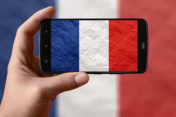 Flaga Francji na ekranie telefonu. Smartfon w ręku fotografowania flagi. — Zdjęcie stockowe