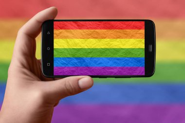 Telefon ekranında Lgbt bayrağı var. Akıllı telefon el kamerasıyla bayrak çekiyor.. 
