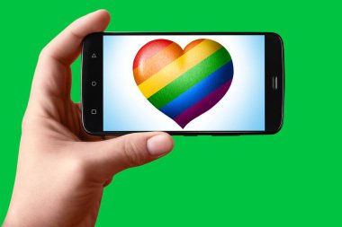 Telefon ekranında kalp şeklinde bir Lgbt bayrağı var. Elinde bir akıllı telefon krom anahtar arka planında bir bayrak kalbi gösterir.