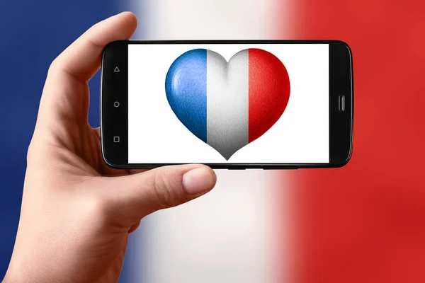 Прапор Франції у формі серця на телефонному екрані. Смартфон у руці показує серцевий прапор.. — стокове фото