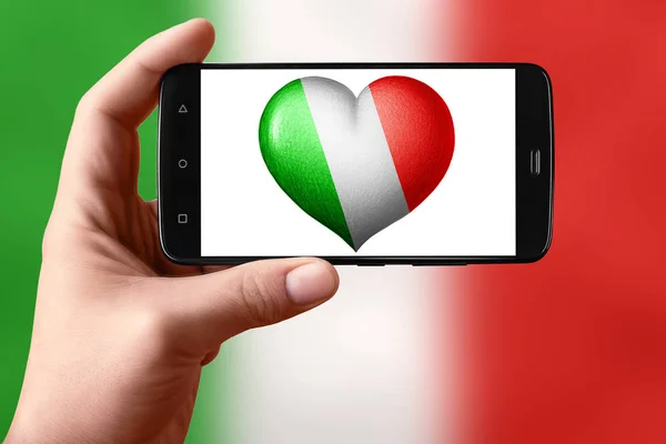 Σημαία Ιταλίας σε σχήμα καρδιάς στην οθόνη. Smartphone στο χέρι δείχνει μια καρδιά σημαία. — Φωτογραφία Αρχείου