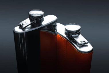 Alkol için iki şişe. Siyah arka planda deri süslemeli çelik mataraların üst görüntüsü. Viski, rom, votka ve çeşitli içkiler için tanklar. 