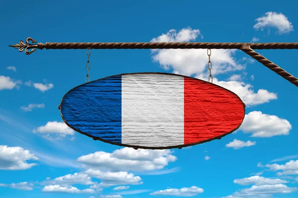 Francouzská vlajka na tabuli. Oválná značka v barvách vlajky Francie zavěšená na kovově kované konstrukci. Šablona na pozadí modré oblohy s mraky. — Stock fotografie