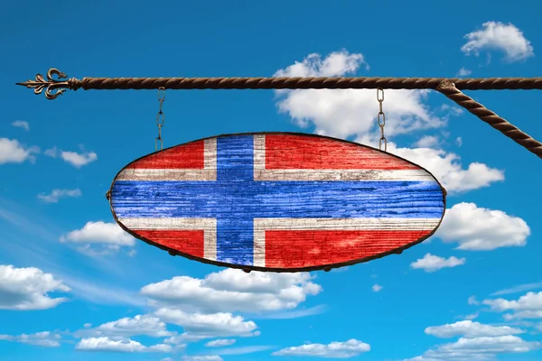 Norway flag on old signboard. Oval sign in the colors of the flag of Norway hanging on a metal forged design. Template on a background of blue sky with clouds.