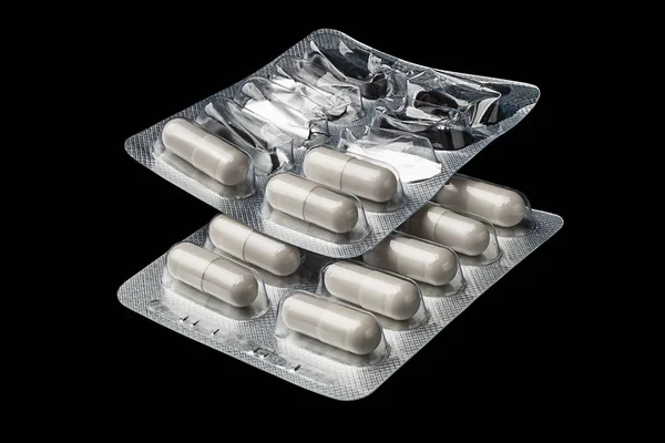 Due blister. Pillole di capsula bianca in un blister intero e aperto su uno sfondo nero. Concetto sanitario. Antibiotici e compresse di capsule antimicrobiche . — Foto Stock