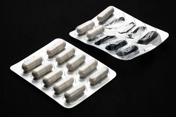 La medicina nel suo complesso e ha iniziato vesciche. Pillole della capsula in blister su sfondo nero. Antibiotici e compresse di capsule antimicrobiche . — Foto Stock