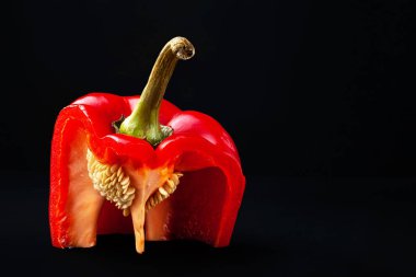 Tohumlu kırmızı dolma biber. Siyah arka planda posası olan dilimlenmiş tatlı biber. Organik yiyecekler. 