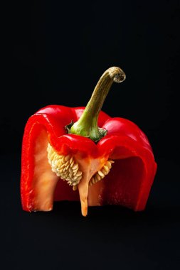 Red sweet pepper with seeds. Close-up of cutting bell peppers with pulp on a black background. Organic food. 