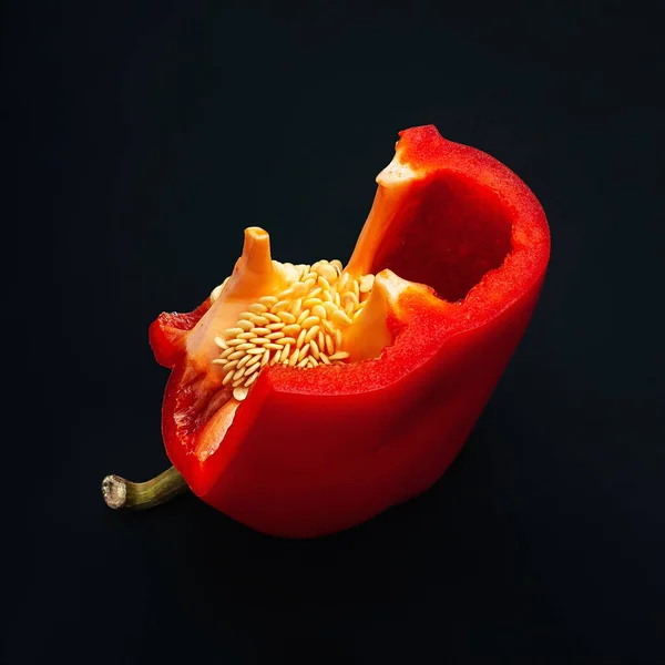 Κόκκινη πιπεριά με σπόρους. Κομμένες πιπεριές σε μαύρο φόντο. Βιολογικά τρόφιμα. — Φωτογραφία Αρχείου