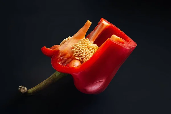 Κόκκινο γλυκό πιπέρι με σπόρους. Κόβω πιπεριές σε μαύρο φόντο. Βιολογικά τρόφιμα. — Φωτογραφία Αρχείου