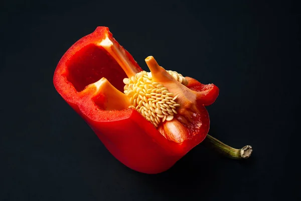 Κόκκινη πιπεριά με σπόρους. Κόβω πιπεριές σε μαύρο φόντο. Βιολογικά τρόφιμα. — Φωτογραφία Αρχείου