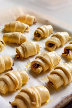 Homemade cakes. Rolls with a sweet filling before baking are folded on parchment paper, on a baking sheet.