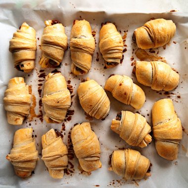 Ev yapımı pişirme. Parşömen kağıdına istiflenmiş bir sürü taze böreğin en üst görüntüsü..