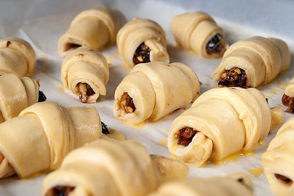 Homemade baking. Sweet rolls with filling before baking are stacked on parchment paper, on a baking sheet.