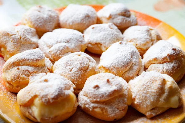 Homemade baking. Freshly baked hot sweet burgers sprinkled with powdered sugar and stacked on a plate. — Stock fotografie