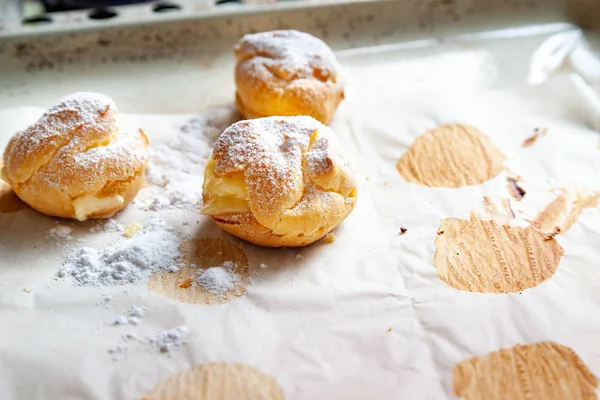 Homemade cakes. Freshly baked hot sweet buns sprinkled with powdered sugar and stacked on baking paper on a baking sheet. — Stock Photo, Image