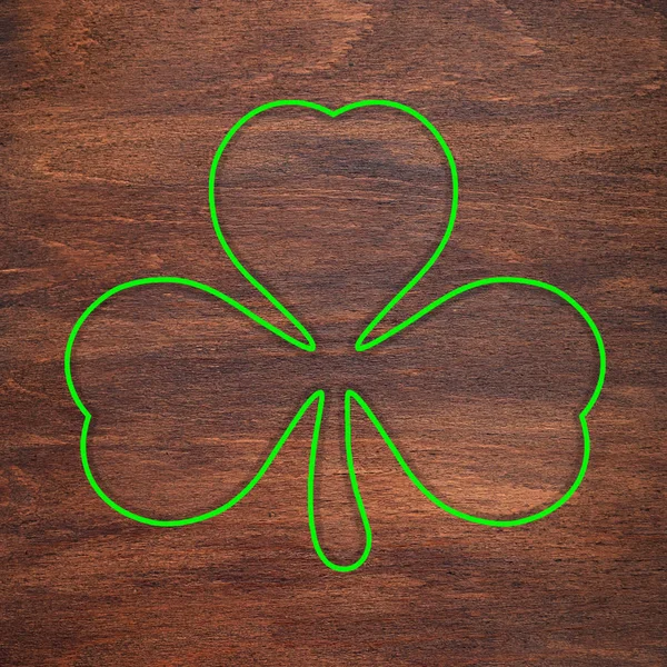 St. Patrick's Day. Green shamrock outline is drawn on a wooden surface. Three leaf clover. — Stock fotografie