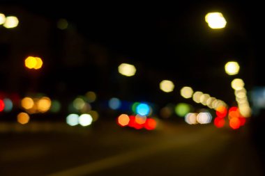 Yolun Bokeh 'i. Şehirdeki sokak lambalarının ve arabaların ışıklarının bulanık görüntüsü. Montaj ve tasarım için yaratıcı arkaplan.