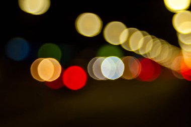 Sokaktaki Bokeh. Şehirdeki sokak lambalarının ve arabaların ışıklarının bulanık görüntüsü. Montaj ve tasarım için yaratıcı arkaplan.