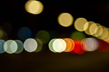 Geceleyin Bokeh caddesinde. Şehirdeki sokak lambalarının ve arabaların farlarının bulanık görüntüsü. Montaj ve tasarım için yaratıcı arkaplan.