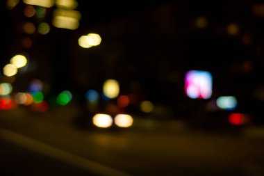 Yaygın ışık otomobil farlarıdır. Şehirde gece sürerken sokak lambalarının ve araba farlarının bulanık görüntüsü. Bokeh elementleri. Montaj ve tasarım için yaratıcı arkaplan.