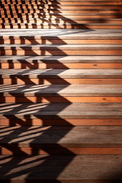 Staircase with a shadow. Staircase with wooden steps and a shadow from the railing. A play of light and shadow in the evening. Conceptual image.