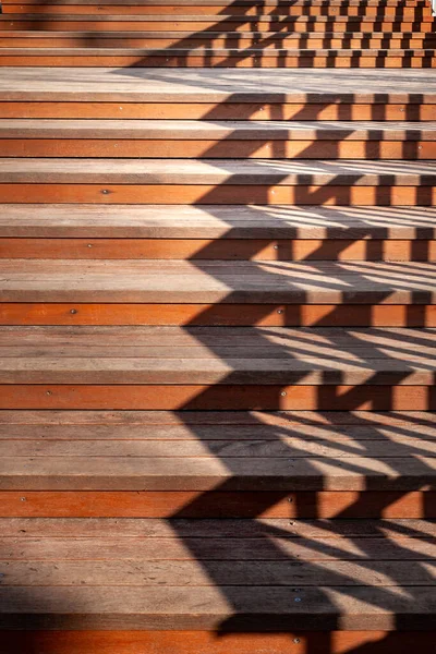 Staircase with shadows from the railing. Close up of a staircase with wooden steps and the shadow of a railing. The play of light and shadow in the evening. Conceptual image.