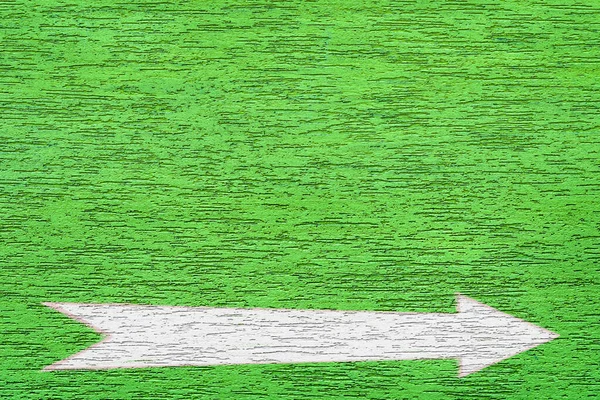 Arrow on a green textured surface. White Pointer painted on the plastered wall of the house. Direction indicator. Signs on the street.
