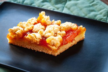 Ev yapımı kayısılı turta. Siyah bir tabakta bir dilim sade, sıcak turta. Doğal organik gıda. Seçici yumuşak odaklanma. Ev mutfağı.