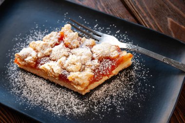 Ev yapımı kayısılı turta. Bir parça kremalı sıcak turta ve siyah tabakta çatal. Doğal organik gıda. Seçici yumuşak odaklanma. Ev mutfağı.