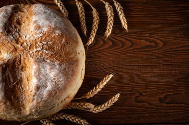 Ev yapımı yuvarlak ekmek. Köylü sıcak ekmeği ve tahtadan bir arka planda, yazı için yeri olan buğday başakları. Ev yapımı pişirme.. 