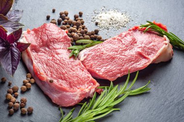Baharatlı çiğ et. Siyah bir taş tabakta taze çiğ et, tuz, biber ve biberiye dilimleri. Izgara et hazırlamak ve marine etmek. Sağlıklı, doğal yiyecekler..