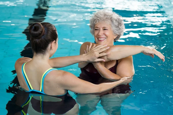 Senior vrouw stretching in zwembad — Stockfoto