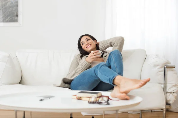 Smiling woman thinking on sofa — Stock Photo, Image