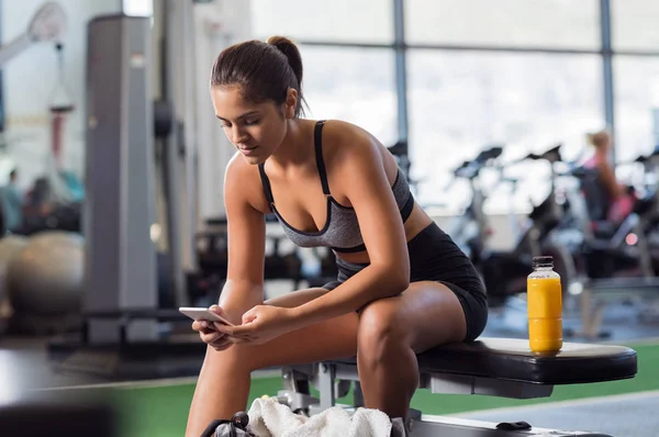 Telefonunuzun ve spor salonunda kadın — Stok fotoğraf