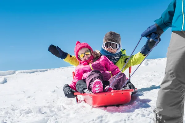 Far som leker med barnen på snö — Stockfoto