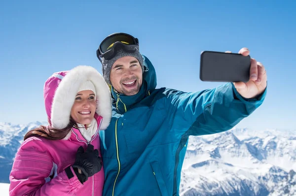 Casal tirando selfie na montanha nevada — Fotografia de Stock