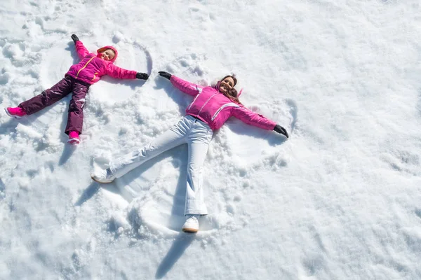 Fille et mère couchées sur la neige — Photo