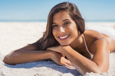 Smiling woman lying on sand clipart