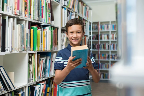 Niño sosteniendo libro en la biblioteca en la escuela —  Fotos de Stock