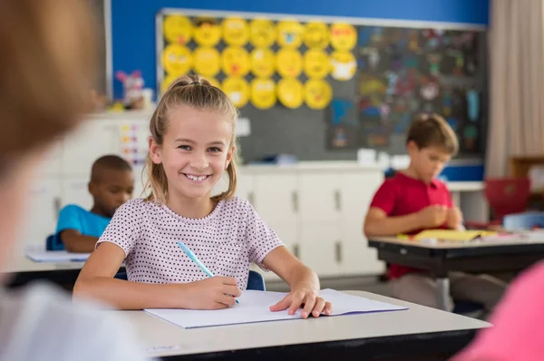 Lächelndes Schulmädchen macht sich Notizen — Stockfoto