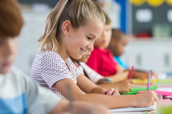 Student tjej skriver om lärobok — Stockfoto