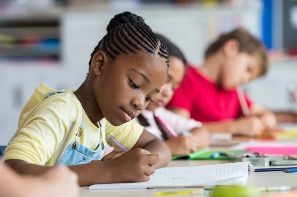 Escola menina escrevendo em classe — Fotografia de Stock