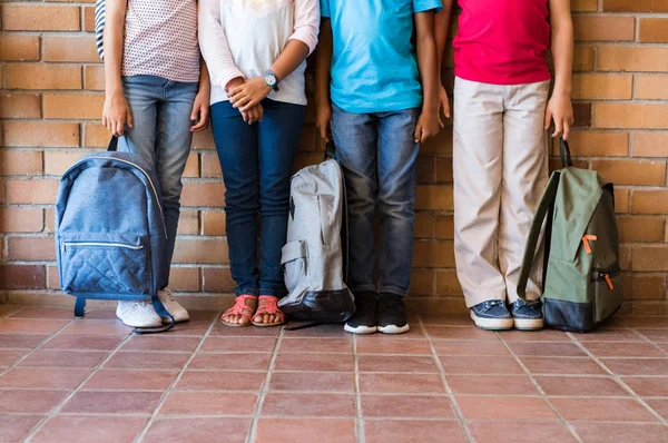 Детские ноги с рюкзаками в школе — стоковое фото
