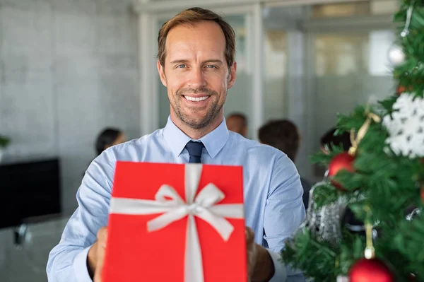 Hombre de negocios sonriente sosteniendo regalo de Navidad —  Fotos de Stock