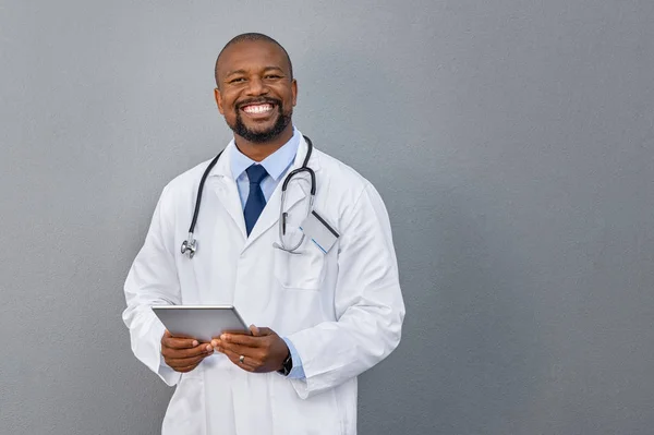 Smiling doctor standing on grey wall — Stock Photo, Image