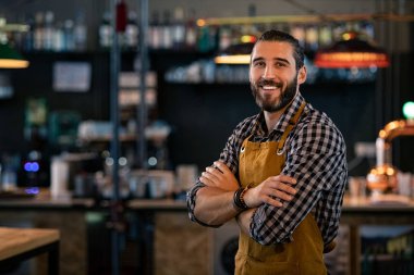 Barmen önlük giyiyor ve gülümsüyor.